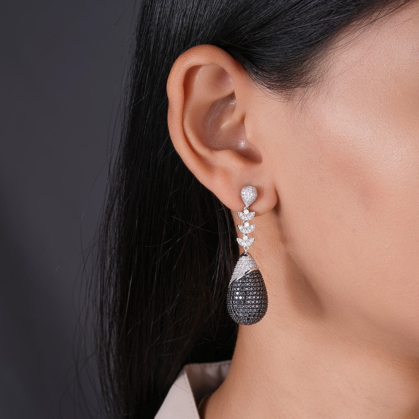 Close-up of a woman wearing a sparkling earring with 'NIRA' branding.